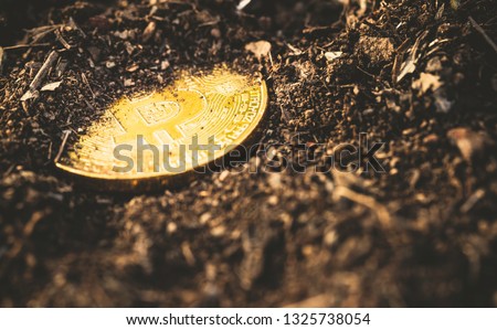 Bitcoin mining and cryptocurrency concept with a golden coin submerged in black land compared to the traditional gold mining