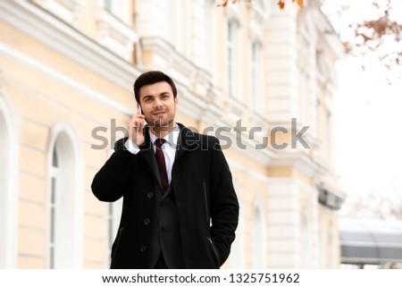 Handsome young businessman talking by mobile phone outdoors