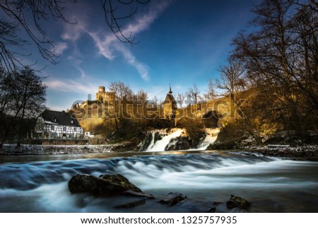 Castle pyrmont in Germany. old castle and bridge with mill on a river with waterfall in winter. langzeitbelichtung