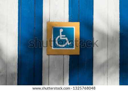 Handicap or wheelchair person icon set on blue and white stripes.