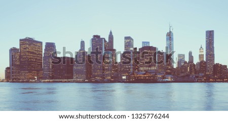 Panoramic view of New York Financial District and the Lower Manhattan at night, viewed from the Brooklyn Bridge Park. Low contrast color image.