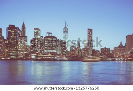 Panoramic view of New York Financial District and the Lower Manhattan at night, viewed from the Brooklyn Bridge Park. Low contrast color image.