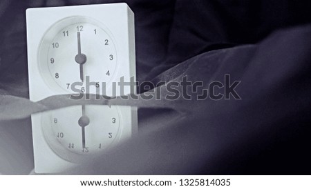Alarm clock (6 o' clock in the morning) on the bed at home. Morning time background concept, soft focusing and vintage color style.