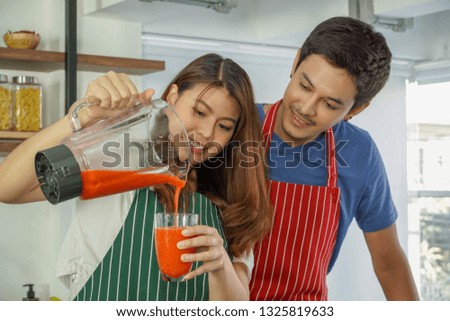 Couples help to make drinks happily. Young men and women help to make drinks happily. Couples are helping each other, enjoying the blending of strawberries on holiday. 