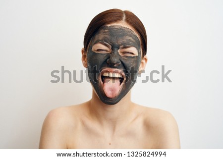 woman in a cosmetic mask shows tongue