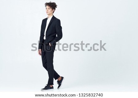 Cute elegant guy in a black suit on a gray background office worker