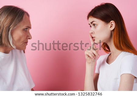 Elderly woman daughter look at each other in a pink background