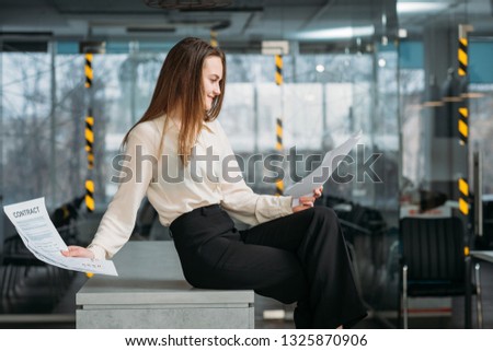 Successful negotiations. Corporate lawyer workplace. Smiling business woman sitting on desk reading contract.