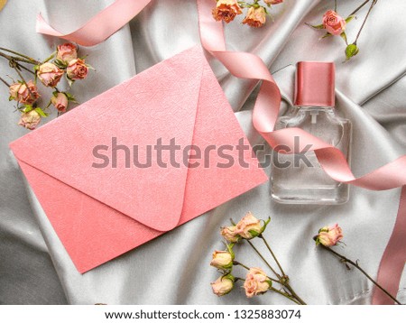 bottle of perfume, flowers and an envelope on a gray satin background