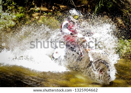Photograph of an enduro pilot, during the crossing of a running stream in the tracks of the Luminaires in Minas Gerais, Brazil
