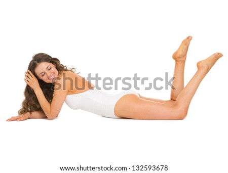 Happy young woman in swimsuit and hat laying on floor