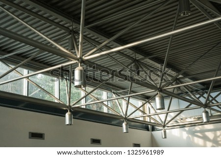 A close-up of a ceiling with lanterns and metal beams in a shopping centre. Inside view of iron structure construction as a background. Industry concept.