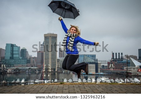 Woman jumps with an umbrella on a foggy cloudy day in Baltimore at Federal Hill Park