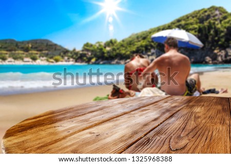 Wooden desk of free space for your decoration. Two young lovers on sand . Beach landscape with sun on blue sky. Summer time. 