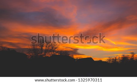 a precipitating pink-orange sky in the countryside against the background of the huts