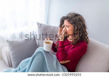 Sick day at home. Asian woman has runny and common cold. Cough. Closeup Of Beautiful Young Woman Caught Cold Or Flu Illness. Portrait Of Unhealthy Girl In Scarf Feeling Pain In Throat. Royalty-Free Stock Photo #1325993255