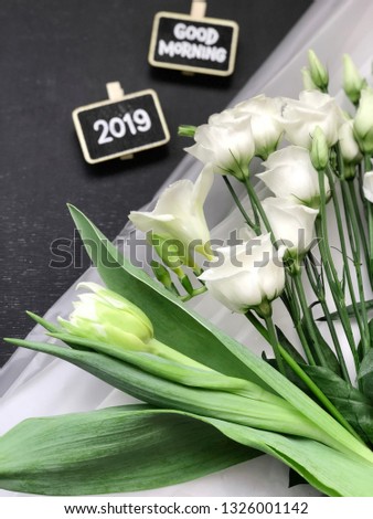spring 2019 flatlay. good morning 2019 spring chalkboard with flowers on black background