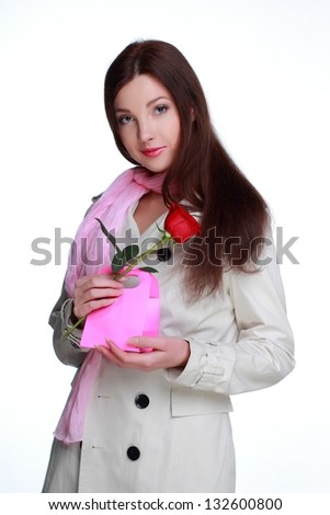 Pretty woman in a beautiful dress holding a single red rose on white background