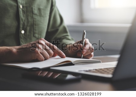The man writes notes to his diary in the office Royalty-Free Stock Photo #1326028199