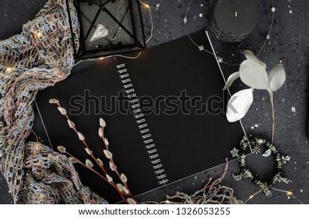 Opened notebook with black sheets on dark background. Top view.