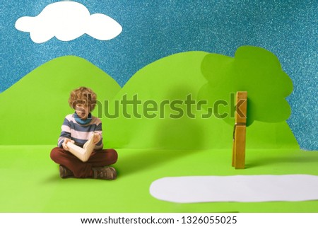 Kid reading a book inside a green cardboard cut out world	