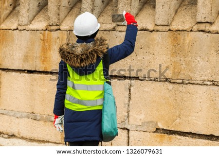 Woman inspector take a pictures on smartphone near concrete wall