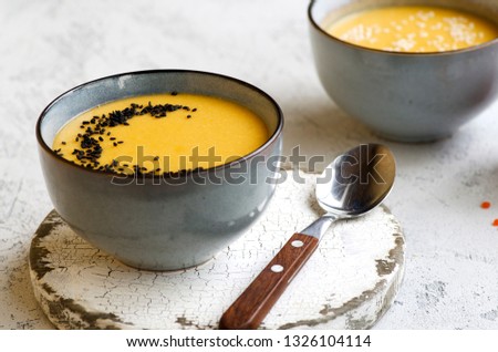 Lunch concept. Kitchen table with two bowls of lentil cream soup, paprika and red lentils in jar Royalty-Free Stock Photo #1326104114