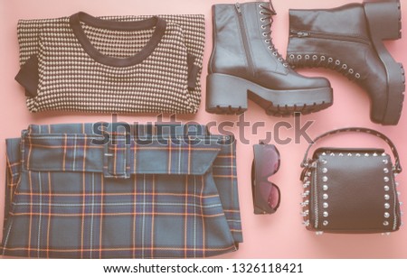 Ladies fashion background on pastel pink, trendy green checked midi skirt, brown jumper, high top heeled boots, studded bag and sunglasses, flat lay, top view, toned photo, copy space, selective focus