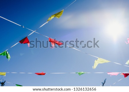 Colored flags against the sun waving in the wind at an outdoor party.