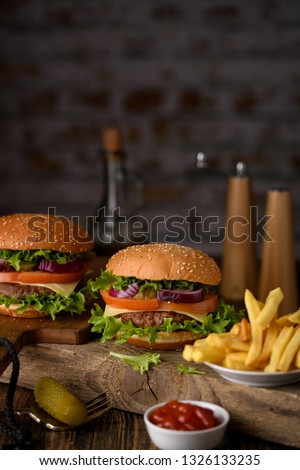 Home cooking burgers and french fries with your hands on a dark wooden background.