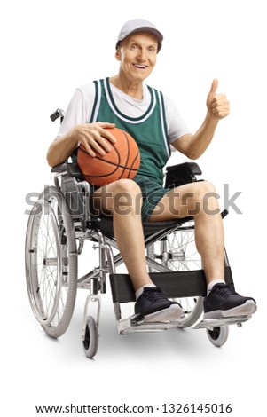 Disabled elderly man in a wheelchair holding a basketball and showing thumbs up isolated on white background
