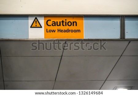 Orange " Caution low headroom " sign on roof above elevators