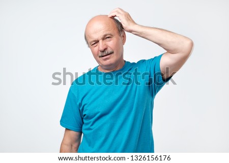 Portrait of casual mature man in blue shirt thinking and looking puzzled.