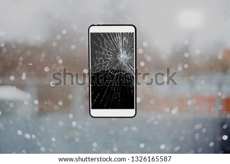 Smartphone with a broken black screen on glass background