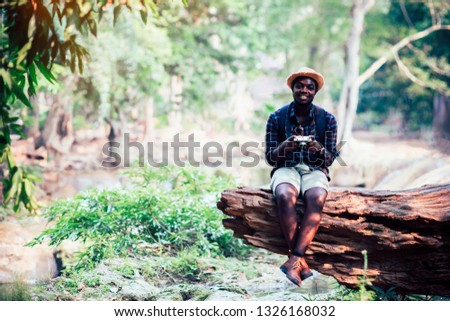 African man traveller sitting on the old tree