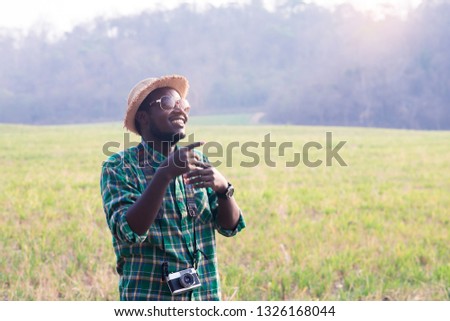 African man traveller holding film camera on a green meadow