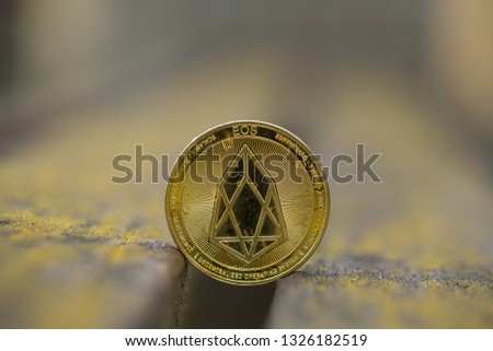 Eos cryptocurrency physical coin placed on the old bench. Macro shot.