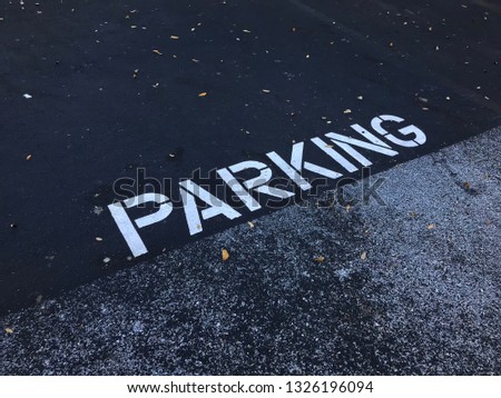 sign showing the word parking painted white paint on asphalt or cement on parking lot