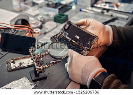 The technician carefully examines the integrity of the internal elements of the smartphone in a modern repair shop