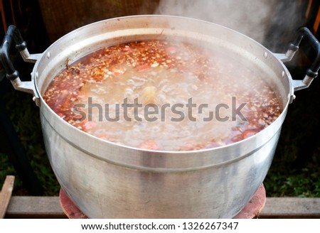 The curry is heated with smoke in a white aluminum pot placed on a charcoal stove.
