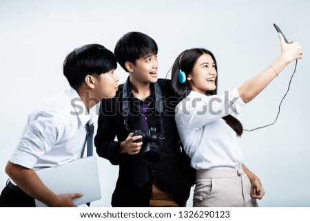 Three young teenagers doing activity together,the beauty lady listening music and taking photo,the middle lady holding camera ,the man at the left side holding laptop in hand,lifestyle of people