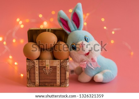 eggs in a chest and easter bunny. Easter concept on pink background. bokeh