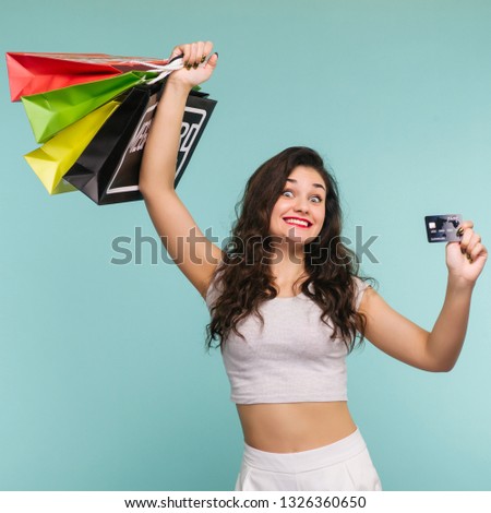 Funny woman with multicolored packages and credit card on a yellow background, shopping - Image