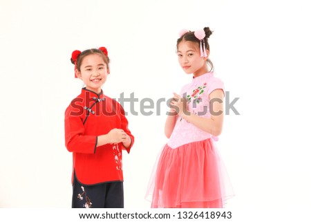 Two young little Asian girl with bun chignon hair  in traditional form dress showing how to say hello or greet with Chinese native style on white background.