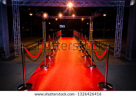 Red carpet with  barriers, velvet ropes and lights in the background Royalty-Free Stock Photo #1326426416