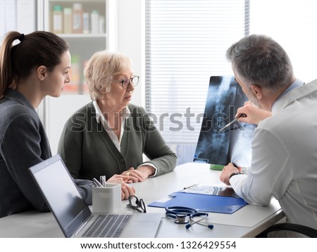 Doctor checking a senior female patient's x-ray image during a visit at the hospital, injury and osteoporosis concept Royalty-Free Stock Photo #1326429554