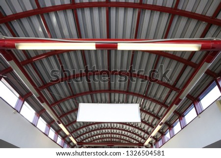 semicircular arch of metal roof. the sign hangs under the ceiling in the subway.  the semicircular carcass of the roof is red. the ceiling of the train station. the ceiling of the ground station metro