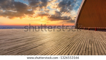Empty wooden platform and modern city skyline with beautiful colorful clouds at sunset