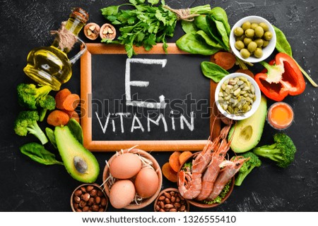 Food containing natural vitamin E: Spinach, parsley, shrimp, pumpkin seeds, eggs, avocados, broccoli. Top view. On a black background.