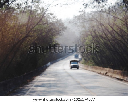 blur defocused view picture of a lonely rural narrow road in tropical lands with green trees and hills plenty of copy space for backdrop or background use  